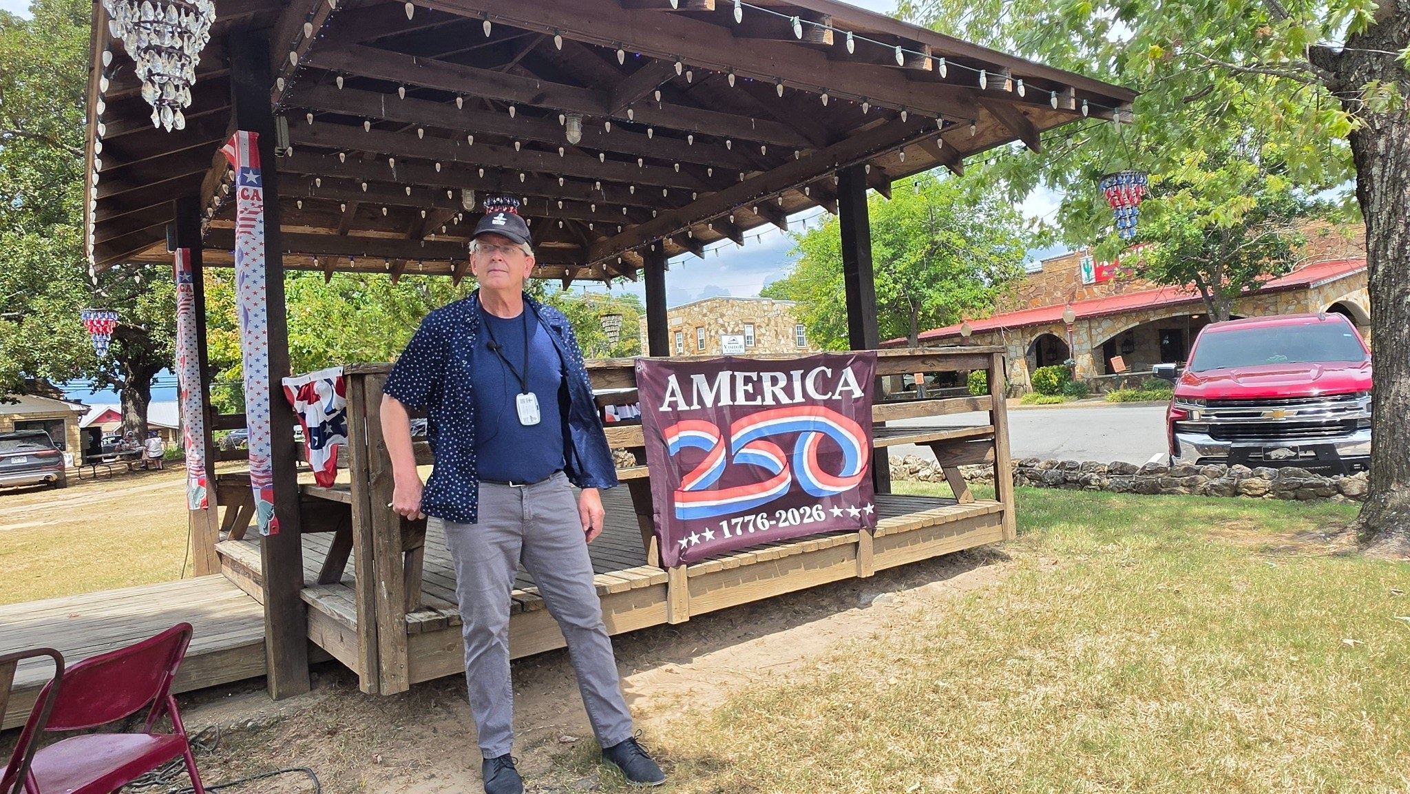 Al Timberlane at the downtown courthouse-square gathering place beside an America 250 banner.