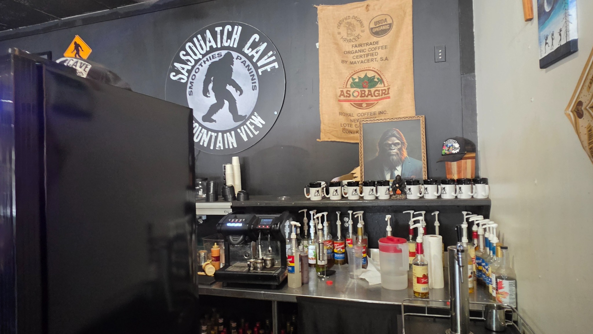 The coffee station, mugs, and Sasquatch Cave sign.