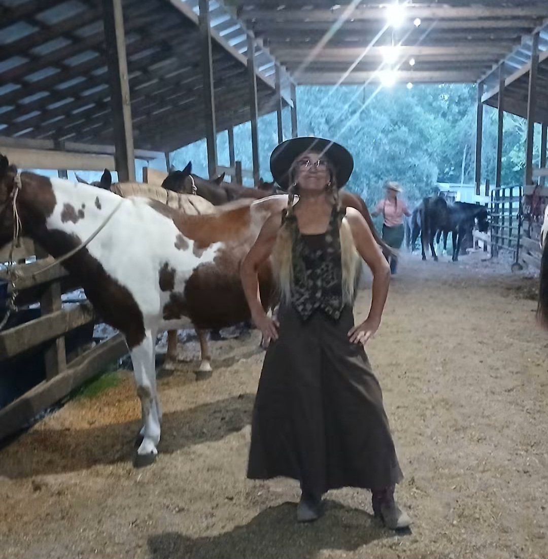 Sharon in her cowboy outfit among horses in the barn at O.K. Trading Post / Poe Ranch.
