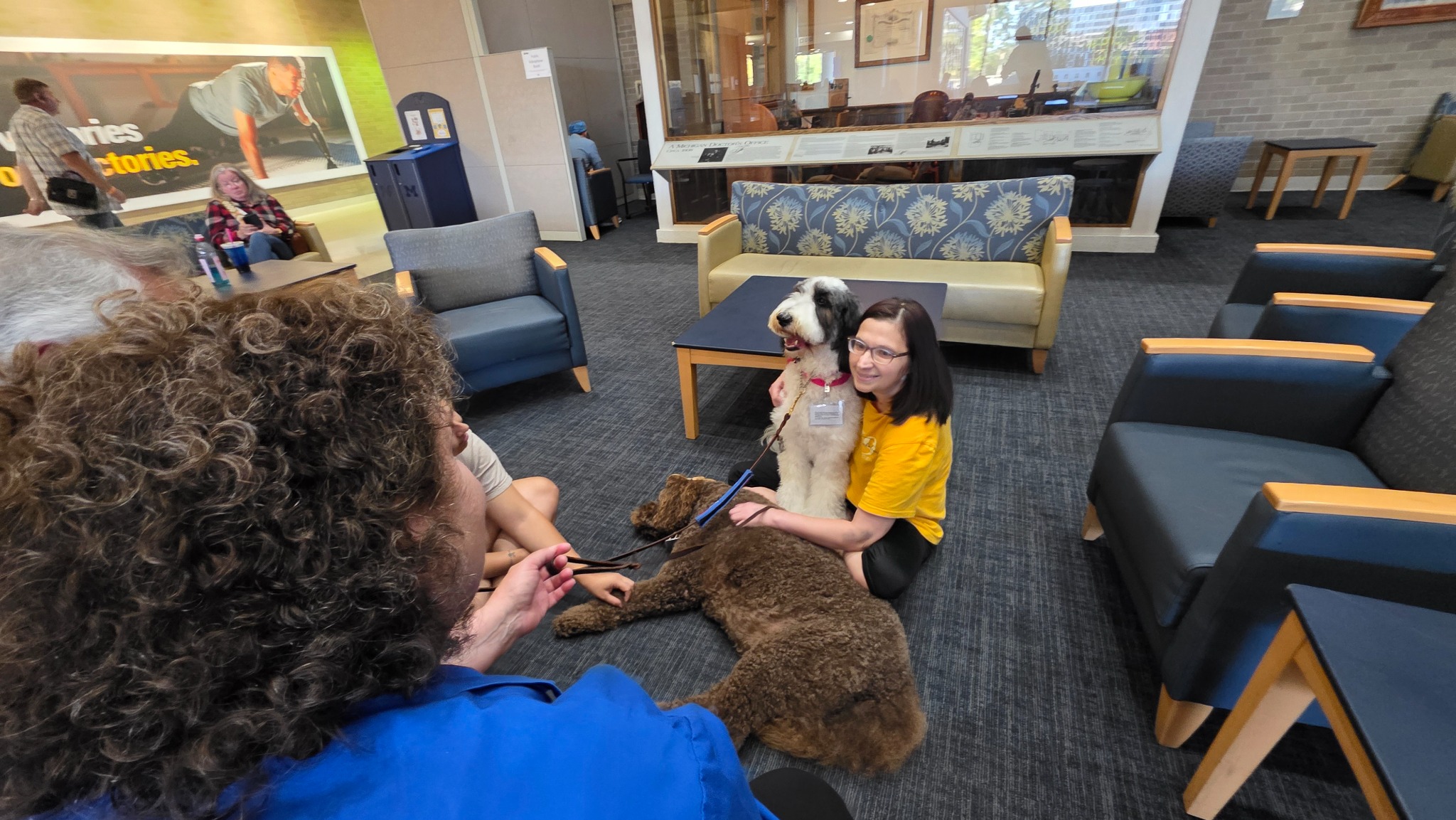 Therapy dogs and visitors gather near the lobby seating
